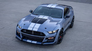 銀色Shelby GT500跑車帶有白色賽車條紋，停在混凝土上。