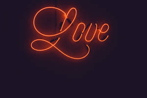 發光的橙色霓虹燈牌，在深色牆上拼出 love。