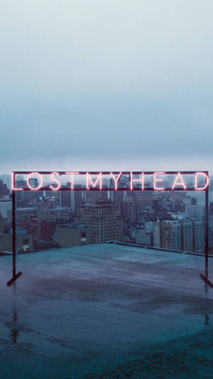 霓虹燈牌寫著 lost my head，位於濕漉漉的屋頂上，俯瞰著黃昏時分的城市。 — 型格動態圖 壁紙