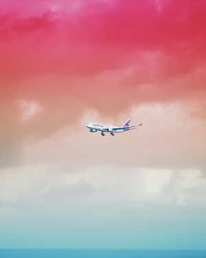 卡塔爾航空飛機在粉紅和青綠色天空下飛越海洋