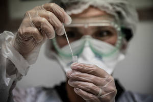 穿著防護裝備的科學家在實驗室中處理試管。