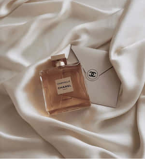 Chanel Gabrielle 香水瓶和信封在奶油色絲綢上。