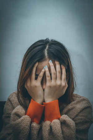 人用手遮臉，身穿棕色抓毛絨和橙色毛衣。 — 憤怒 壁紙