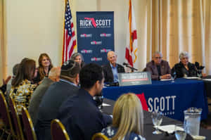 Rick Scott 在政治活動中與支持者和競選橫幅一起。