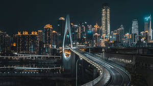 夜間水上發光的橋樑，映襯著充滿活力的城市天際線。 — 花城 壁紙