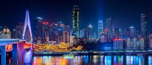 夜晚燈火通明的城市天際線，有橋樑和河流倒影。 — 唐人街 GIF 壁紙