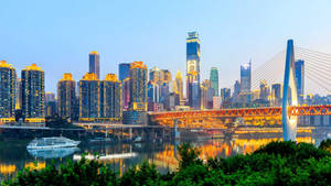 黃昏時分，城市天際線與燈火通明的建築物和水面上的橋樑。 — 唐人街 GIF 壁紙