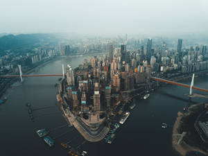 從高空俯瞰，沿河而建的密集現代城市，有橋樑和船隻。 — 唐人街 GIF 壁紙