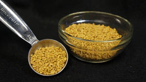 金屬匙和裝滿金色葫蘆巴籽的玻璃碗在深色表面上。 — 清新 GIF 壁紙