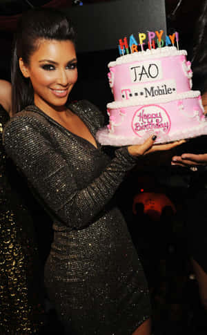 Kim Kardashian 在派對上手持一個品牌生日蛋糕。