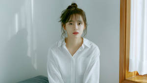 身穿白恤衫的年輕女性坐在窗邊，柔和自然光。