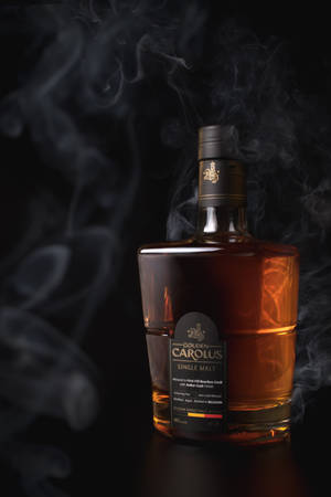 Golden Carolus 威士忌酒瓶，煙霧在黑暗表面上環繞。
