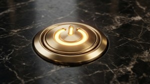 發光金色電源按鈕置於深色大理石表面。