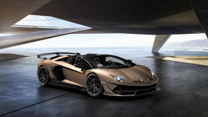 青銅色林寶堅尼Aventador SVJ Roadster停放在海邊的現代混凝土建築下。