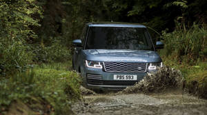 銀色 Range Rover 在泥濘森林小徑上行駛。