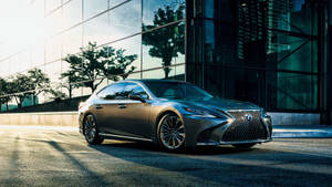 銀色 Lexus 房車停泊在帶有玻璃建築倒影的城市街道上。