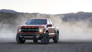 紅色福特 F-150 Raptor 貨車在日出時分駛過沙漠，揚起塵雲。