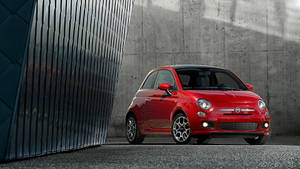 紅色Fiat 500停放在混凝土和金屬牆壁旁。