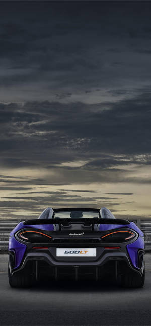 在黃昏的賽道上，帶有戲劇性雲彩的紫色McLaren 600LT Spider。