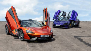 兩輛McLaren超級跑車在藍天下打開車門停在碎石場上。