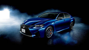 藍色Lexus GS F轎車在煙霧瀰漫的黑暗攝影棚中被聚光燈照亮。