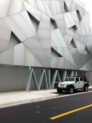 白色Jeep停在幾何現代建築前。