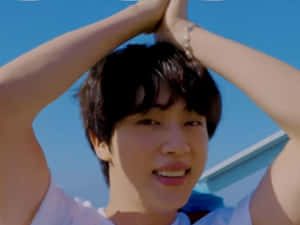 年輕男子在明亮藍天下舉臂微笑