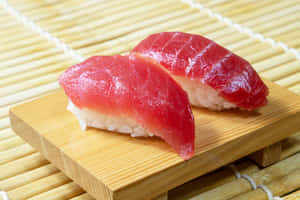 竹蓆背景的木碟上兩件吞拿魚壽司。 — 宿儺 壁紙