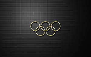 金色奧運五環在黑色穿孔金屬表面上。