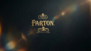 金色Parton標誌帶有裝飾性花紋，位於深色紋理背景上，伴有鏡頭光暈。