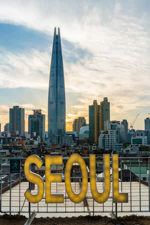 金色首爾標誌俯瞰日落時嘅城市天際線，背景有一座高塔。 — Lenovo Legion Y900 13 壁紙