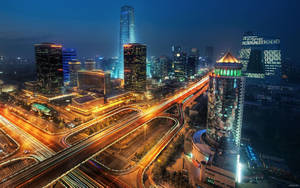 夜間城市，摩天大樓亮起，高速公路上有發光的交通軌跡。