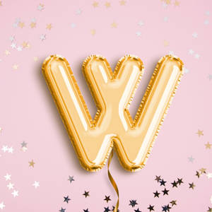 金色字母W氣球被星星紙屑包圍在粉紅色背景上