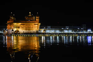 金色寺廟在夜間發光，水面倒映，人們聚集在周圍。 — MacBook Air 15 壁紙