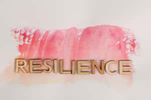 木製字母在粉紅色水彩背景上拼出 resilience。