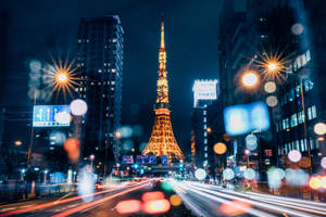 夜晚點亮的東京鐵塔，帶有車燈軌跡和雨滴散景效果。 — 日本 壁紙