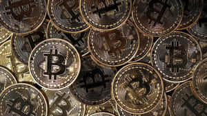 一堆帶有雕刻符號的金色比特幣加密貨幣硬幣。 — 比特幣 壁紙