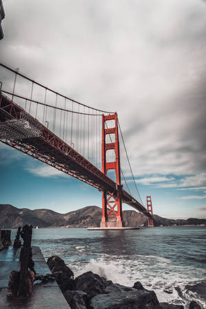 黃昏時分的金門大橋，海浪拍打下方岩石。