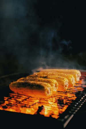 夜晚在熾熱的炭火上燒烤的粟米，煙霧裊裊升起。 — POCO Pad 壁紙
