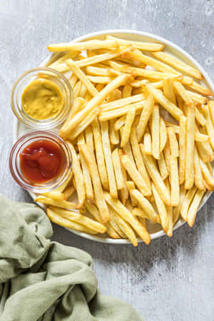 金黃酥脆的薯條配上番茄醬和芥末醬，放在碟上，旁邊有綠色餐巾。 — Vivo Pad SE 壁紙