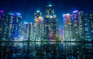 夜晚城市天際線，摩天大樓與水面倒影 — 紐約市夜晚 壁紙