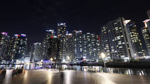 夜間城市天際線，發光的建築物和人們沿著海濱長廊散步。 — 夜景城市 壁紙
