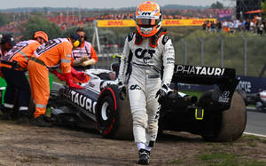 F1車手從受損的AlphaTauri賽車旁走開，維修人員正在處理。