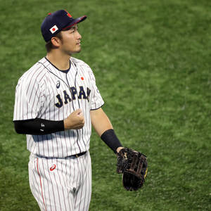 身穿球衣的日本棒球選手在球場上戴著手套並握拳。