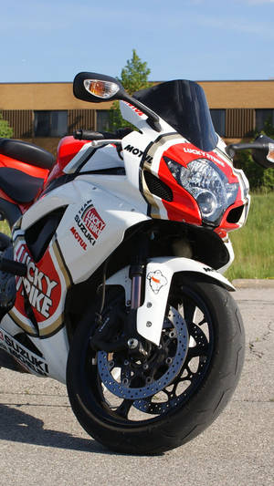 紅白色Suzuki電單車帶有Lucky Strike貼紙，停泊在人行道上。