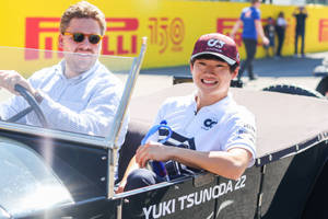 兩個人在賽車裡在晴朗的日子對著鏡頭微笑。