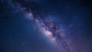 銀河系在黑暗的夜空中散發著紫色和藍色的星星。