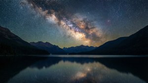 夜晚被山脈環繞的平靜湖泊中倒映的銀河系