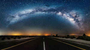 一條黑暗的道路在星空下延伸，上方可見銀河。
