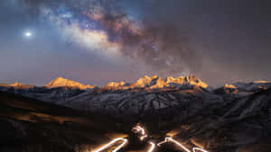 星空下的雪山，發光的道路痕跡蜿蜒穿過山谷。 — 銀河系 壁紙